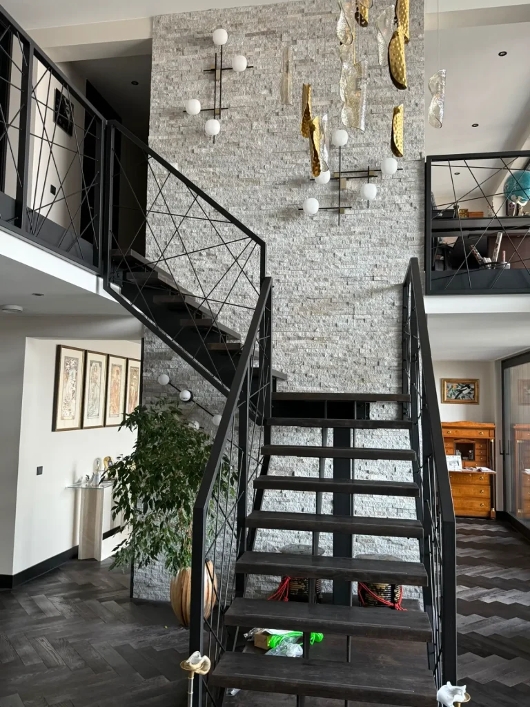 Moderne zwarte stalen trap met open houten treden en stalen balustrade met geometrisch ruitpatroon