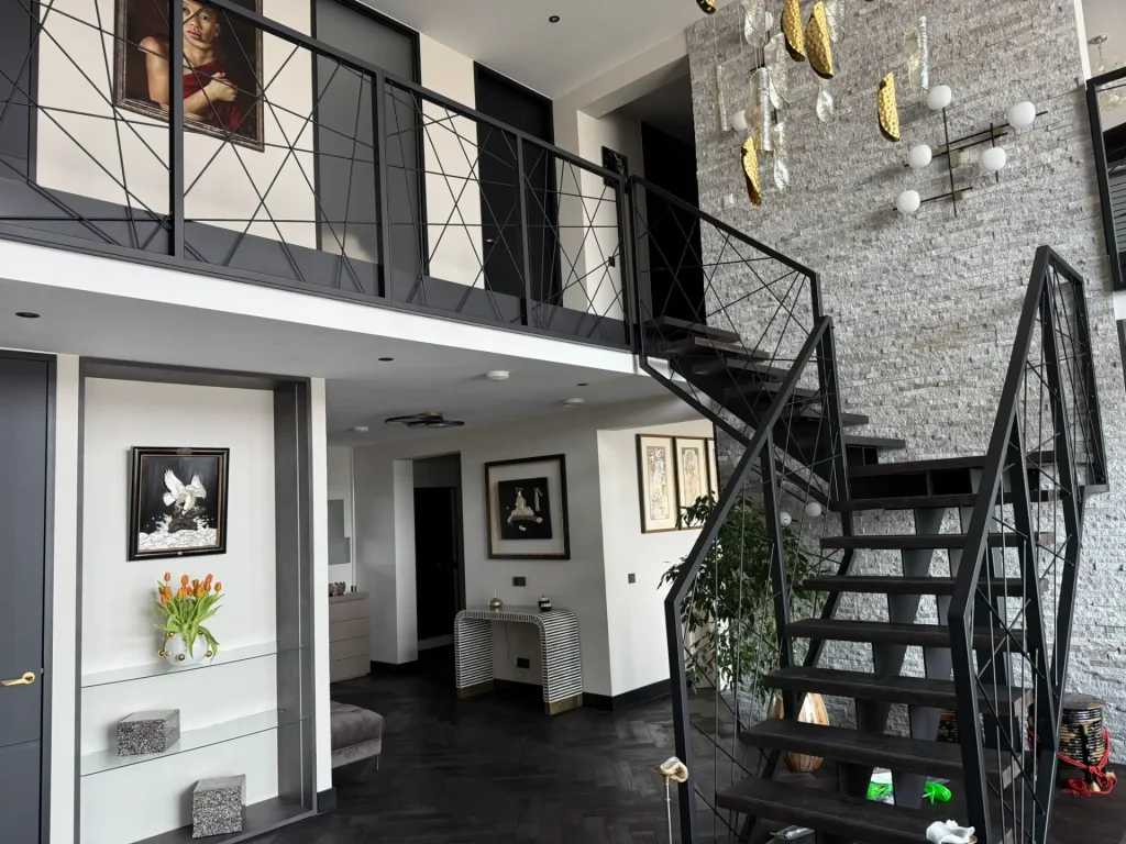 Moderne zwarte stalen trap met open houten treden en stalen balustrade met geometrisch ruitpatroon